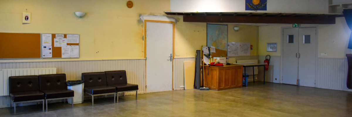 Salle avec chaises, tableau, porte, bureau et affiches.