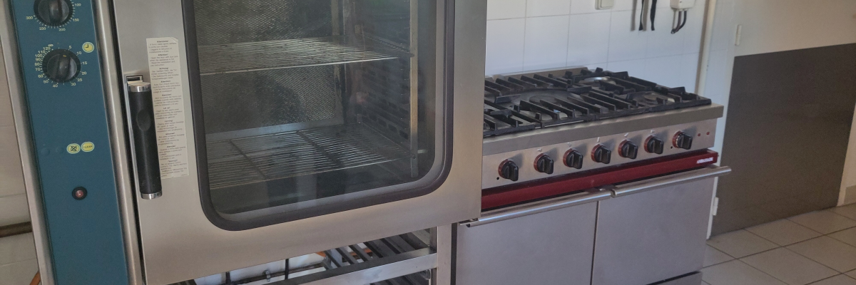 Cuisinière à gaz, four et étagère de rangement dans une cuisine.