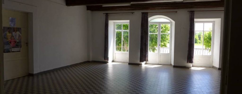 Pièce vide avec carreaux au sol, fenêtres et porte vitrée.