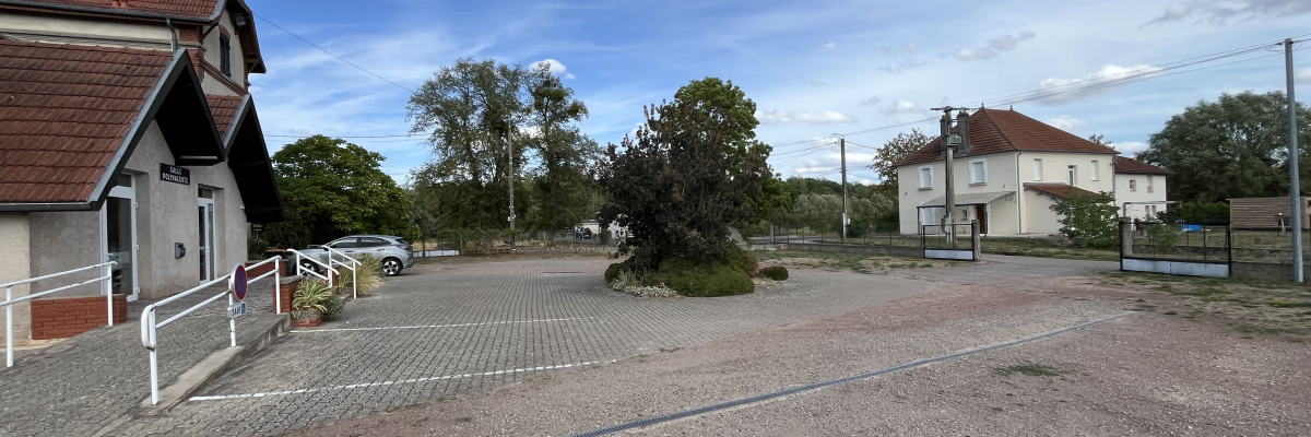 Parking avec bâtiments, voitures et arbres.