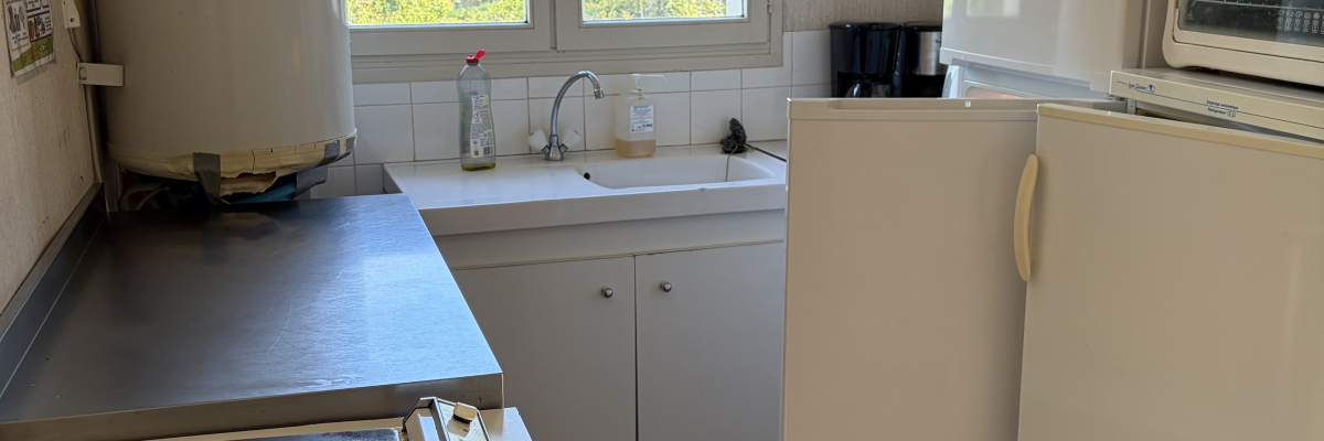 Cuisine avec four, plan de travail, évier, micro-ondes, réfrigérateur et fenêtre.