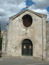 Église en pierre avec rosace, entrée principale et portes fermées.