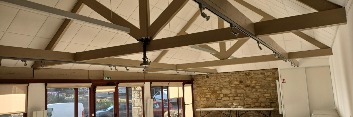 Salle avec poutre, sol carrelé, fenêtres, voiture dehors.