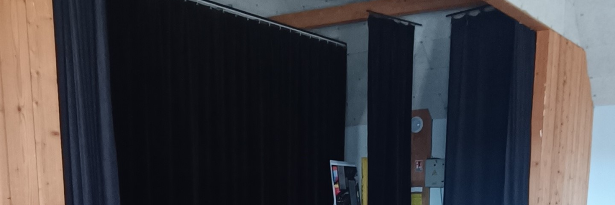 Salle avec rideaux, chevalet et table.