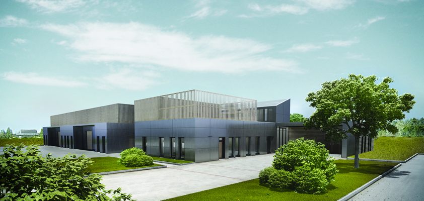 Bâtiment moderne avec façade en verre et en métal, entouré d'arbustes et d'arbres, avec une allée et une route.