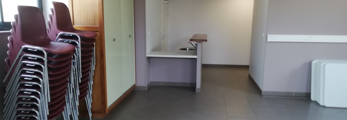 Pièce avec empilement de chaises, armoire, lavabo, miroir et porte.