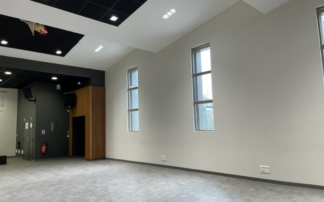 Pièce vide avec fenêtres, éclairage encastré, portes, et interrupteurs muraux.