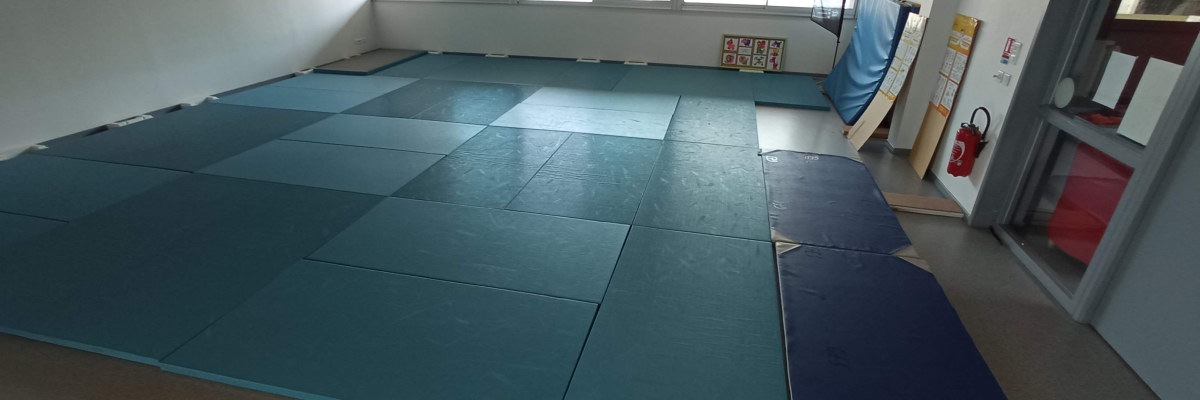 Salle avec tapis bleu, extincteur, porte, et fenêtres.