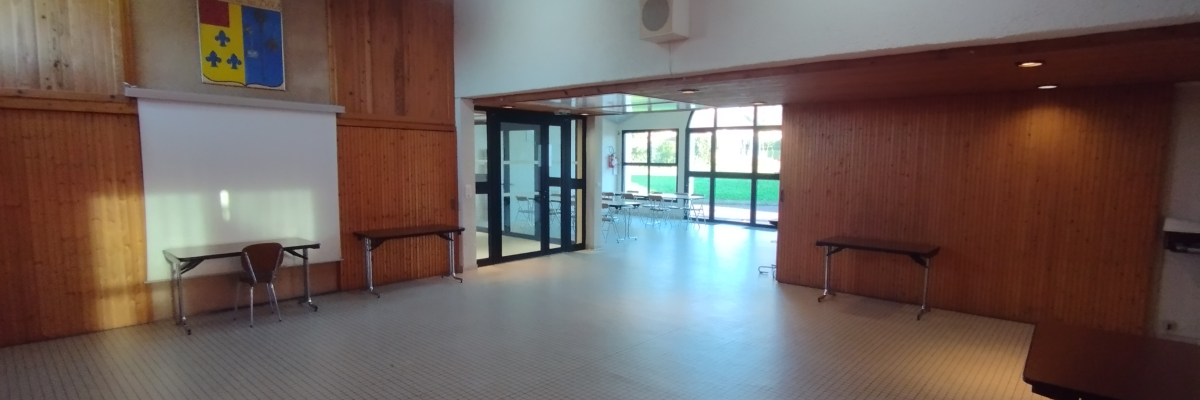 Salle avec tables, bancs, porte vitrée et murs en bois.