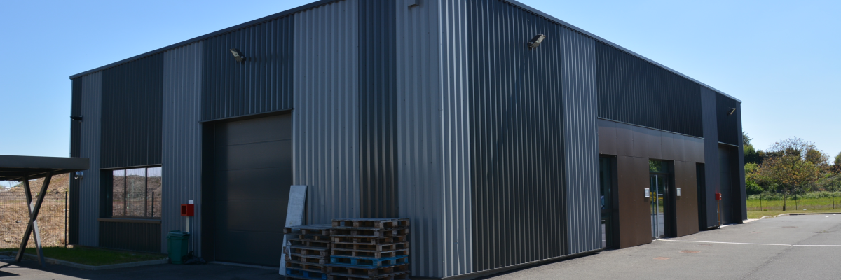 Bâtiment industriel avec porte de garage, palettes et extincteur.