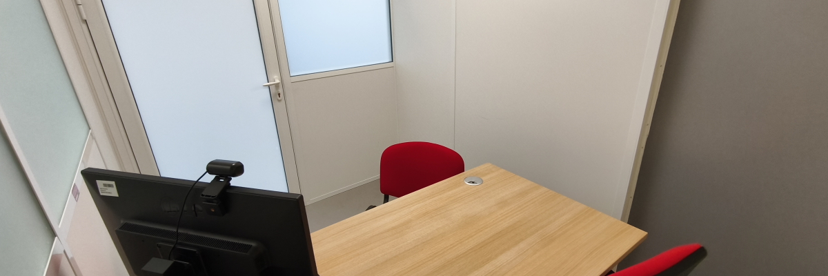 Salle avec table, chaises, ordinateur, clavier et souris.