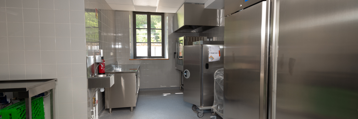 Cuisine avec plans de travail, éviers, fours, réfrigérateurs et chariot.