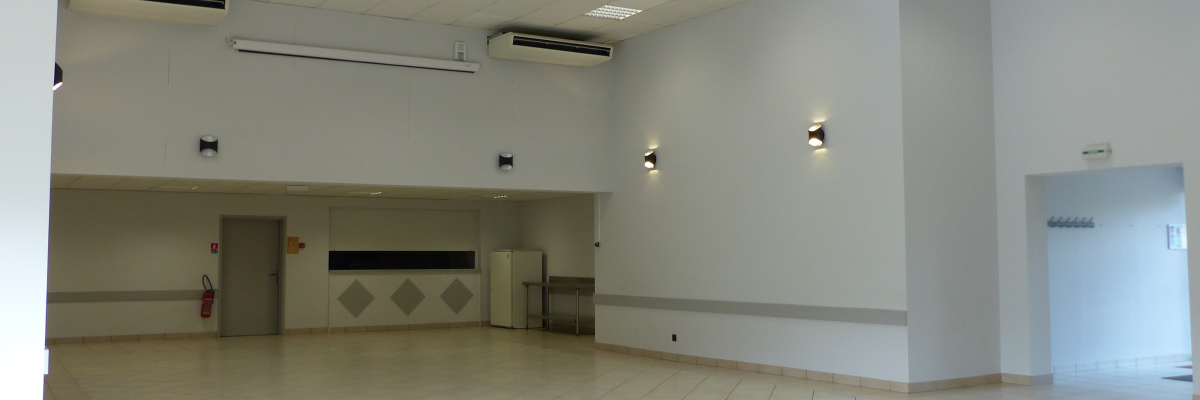 Salle vide avec éclairage, climatisation, porte, extincteur et mur décoré.