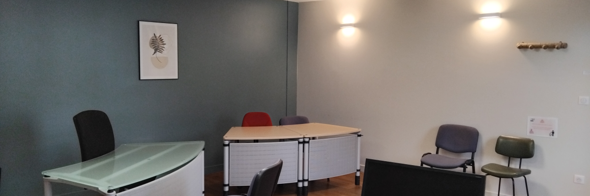 Bureau avec tables, chaises, ordinateurs, lumière et tableau.