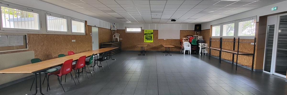 Salle avec tables, chaises, affiches, placards et rangements.