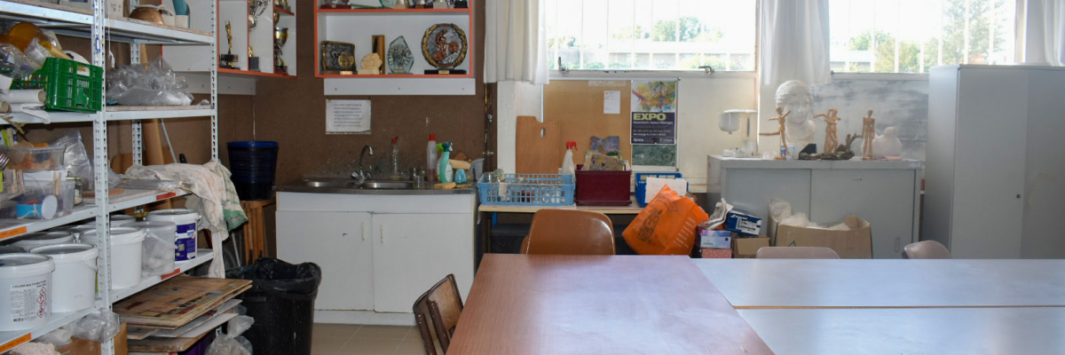 Pièce avec tables, chaises, étagères, trophées, matériel divers.