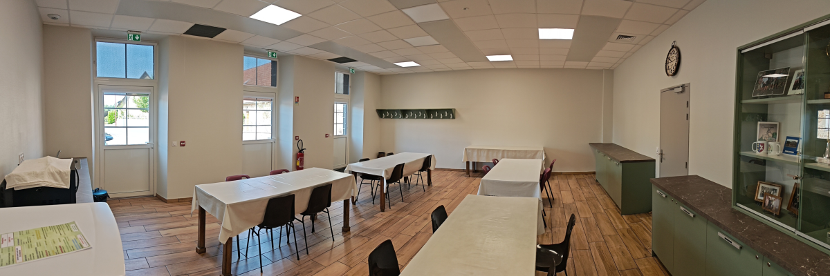 Salle avec tables, chaises, vitrine, horloge, extincteur, porte et fenêtres.