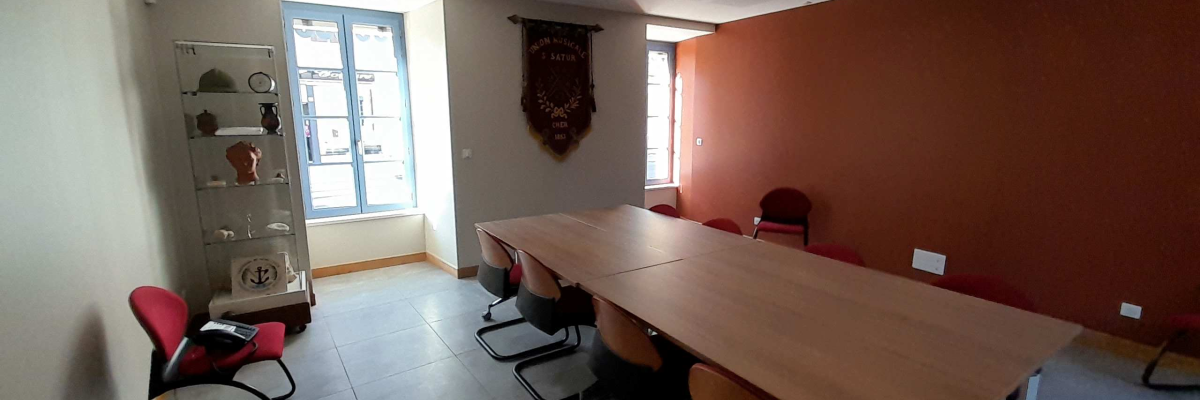 Salle de réunion avec table, chaises, vitrine d'exposition et drapeau mural
