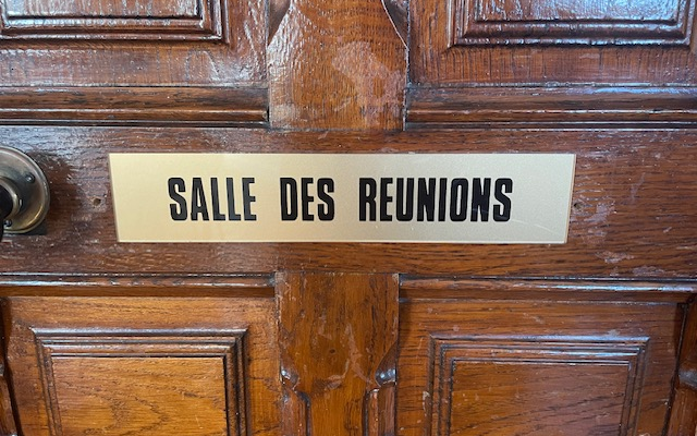 Porte en bois avec une pancarte "Salle des Réunions" et une poignée.
