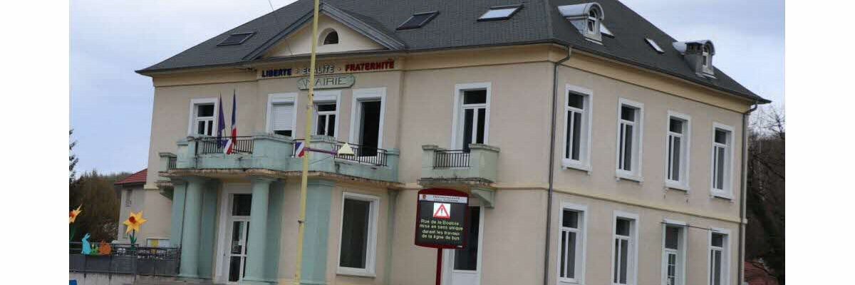 Maison de ville avec enseigne, drapeaux, mats, bancs et panneau de signalisation.