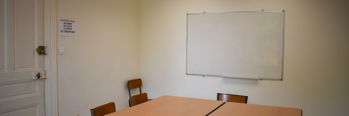 Salle avec table, chaises, tableau blanc et porte.