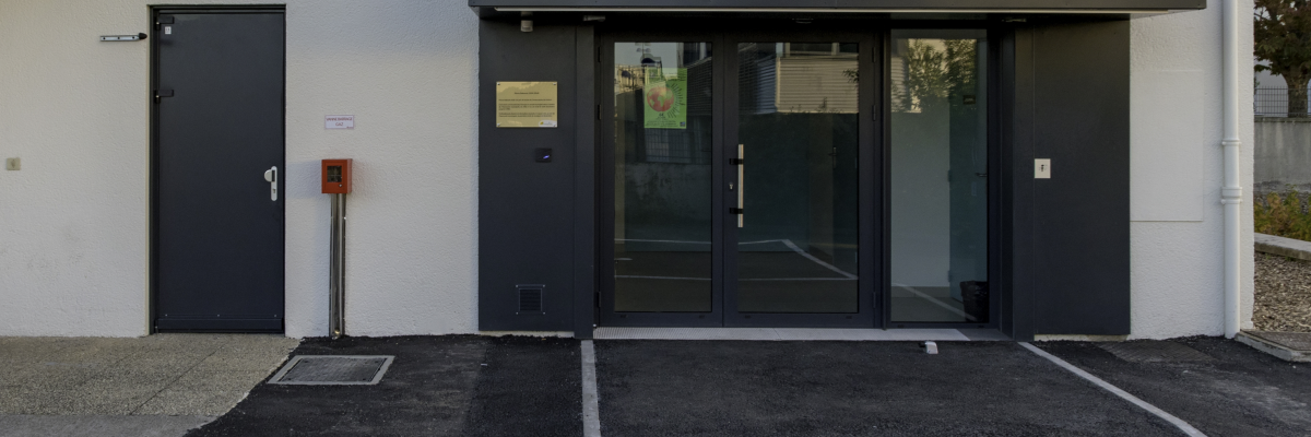 Bâtiment avec porte, vitres et enseigne "Salle Pierre Sabourin". Place de parking marquée "PR".