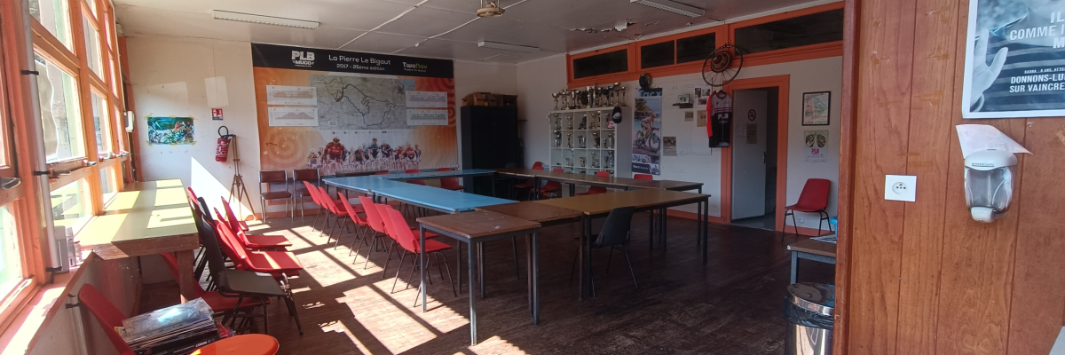 Salle avec tables, chaises, panneau d'affichage, porte-manteau et fenêtre.