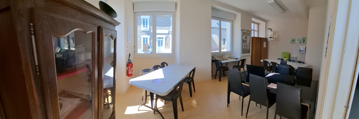 Salle avec table, chaises, armoire et fenêtres.