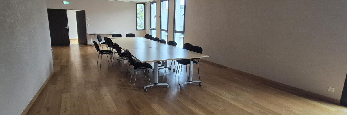 Salle de réunion avec table, chaises et fenêtres.