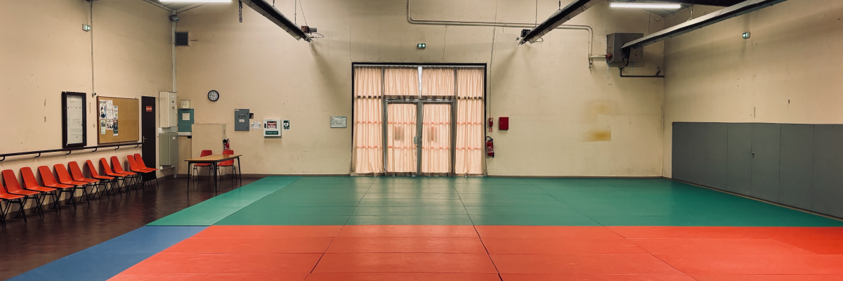 Salle avec tapis colorés, chaises, table, et portes.