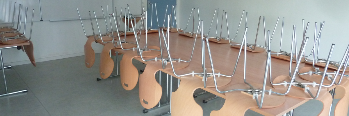 Salle avec tables, chaises, tableau et support de projecteur.