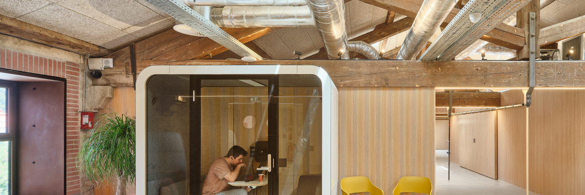 Bureau moderne avec cabine de travail, chaises, table basse et plantes.