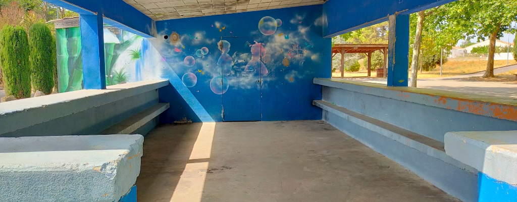 Abri avec bancs, murs bleus et peinture murale.