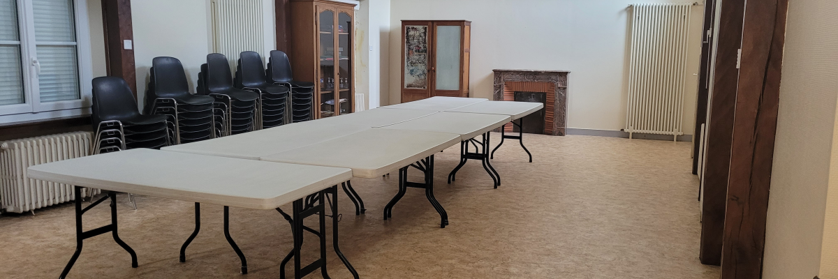 Salle avec tables, chaises, radiateurs, porte et fenêtres.