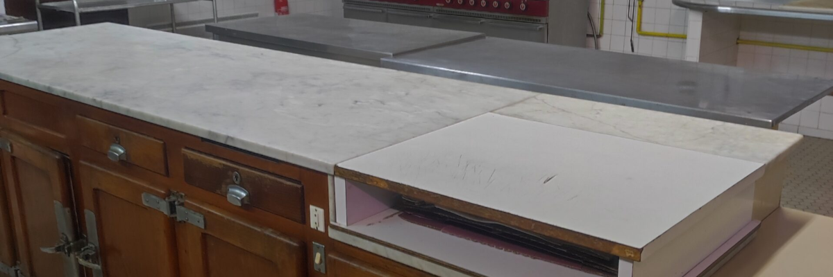 Cuisine avec plan de travail, fours, évier, hotte et lumières.