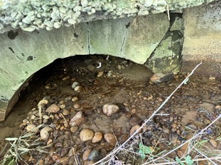 Archway en béton avec des pierres et des débris à l'intérieur et autour.