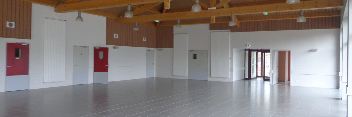 Salle spacieuse avec sol carrelé, plafond en bois et luminaires industriels, portes rouges et blanches.