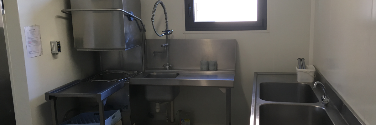 Cuisine industrielle avec évier, plan de travail, lavaire et hôte aspirant.