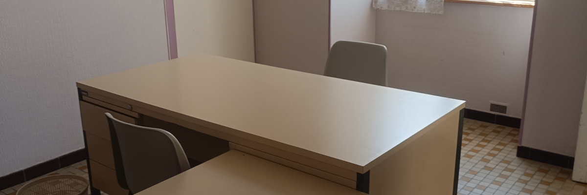Bureau avec table, chaises, tiroirs et fenêtre.
