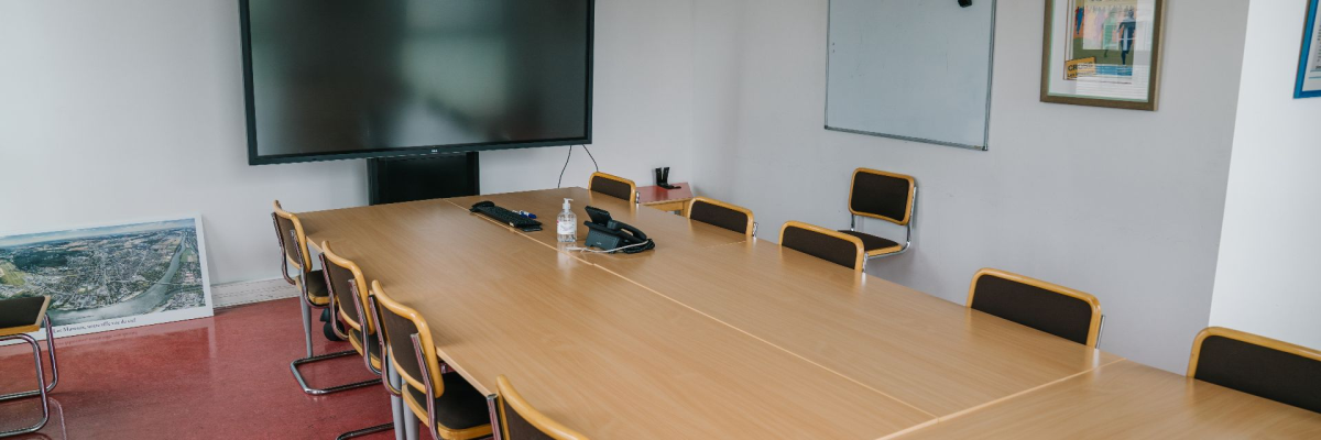 "Salle de réunion avec table, chaises, écran, tableau blanc et micro".