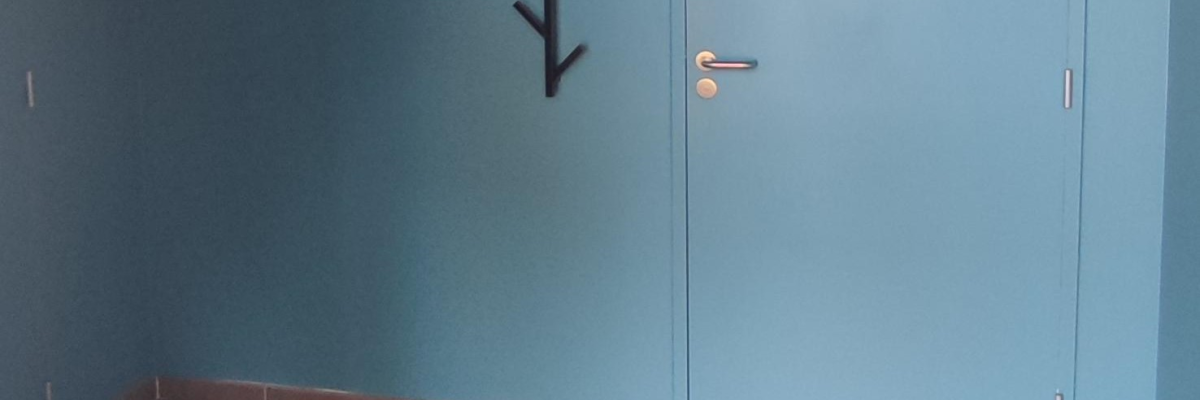 Pièce vide avec porte, porte-manteau mural, poignée et serrure.