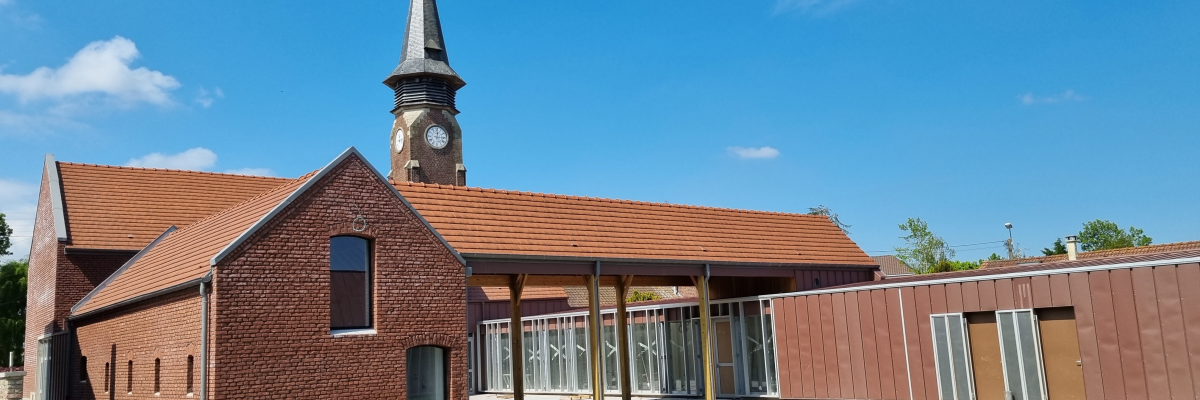 Église avec clocher, toit en tuiles, murs en briques, entrée vitrée et pelouse.