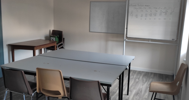 Salle avec table, chaises, tableau blanc et paperboard.