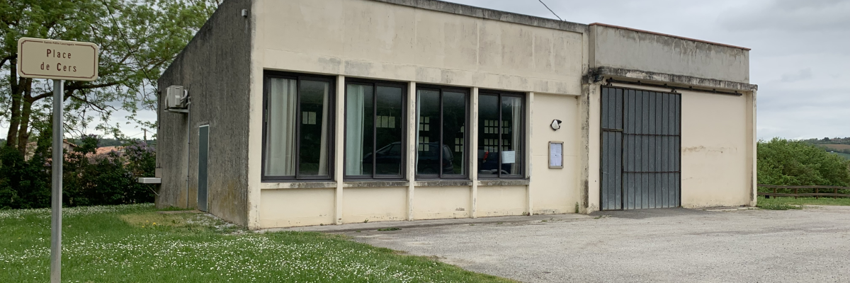 Bâtiment avec grandes fenêtres, porte de garage et panneau de signalisation à côté.