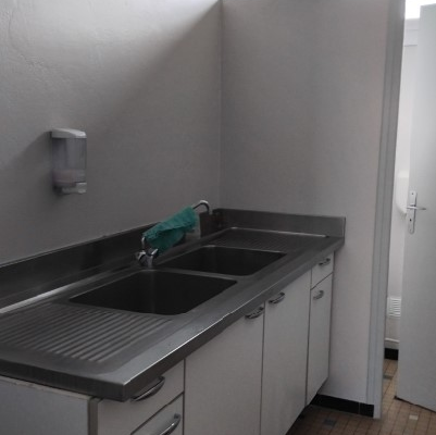 Cuisine avec évier, meubles de rangement et savon liquide.