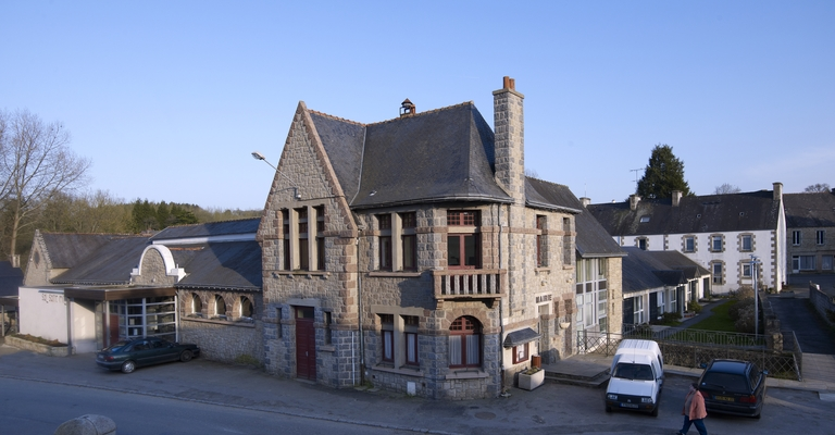 Bâtiment en pierre avec cheminée, voitures et piétons.