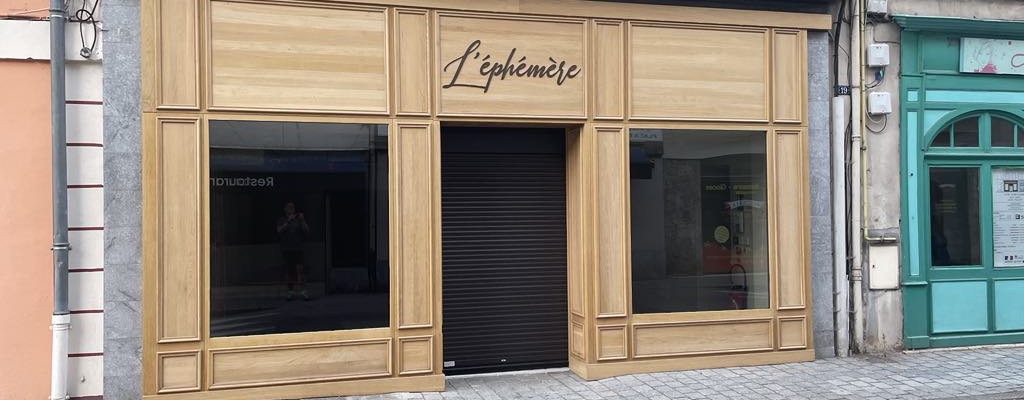 Boutique avec devanture en bois, vitrines et rideau métallique.