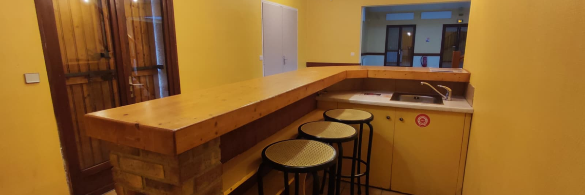 Cuisine avec comptoir, tabourets, évier, placards et luminaires suspendus.