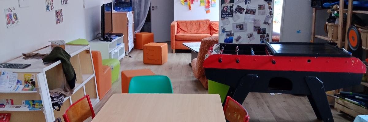 Salle avec table, chaises, canapé, baby-foot et divers jouets.