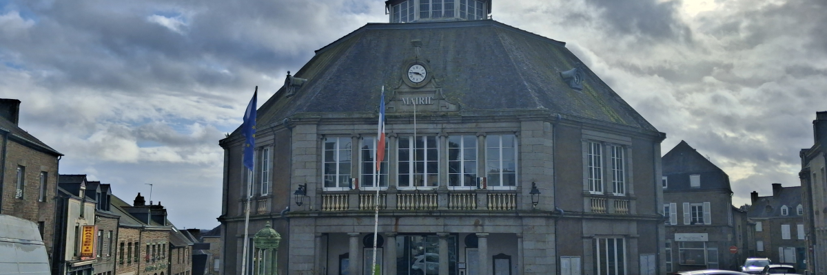 Mairie avec toit octogonal, horloge, drapeaux, voitures et panneaux de signalisation.